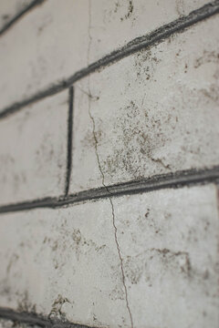 Distressed faux brick wallpaper with cracks and weathered texture, providing a grunge industrial background for construction, renovation and graphic design
