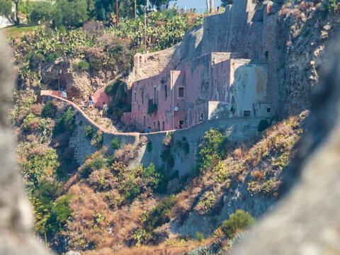 Sanctuary of Saint Anthony of Padua carved into the cliff face at Cape Milazzo, Sicily, Italy. Historic rock-hewn church facade nestled on rugged coastal slope along scenic Mediterranean pathway.