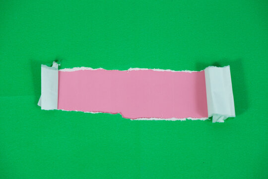 A layer of pink paper behind a torn sheet of green paper. A torn paper section reveals a pink background with space for text. The torn green paper layer peels back, exposing the pink layer underneath.