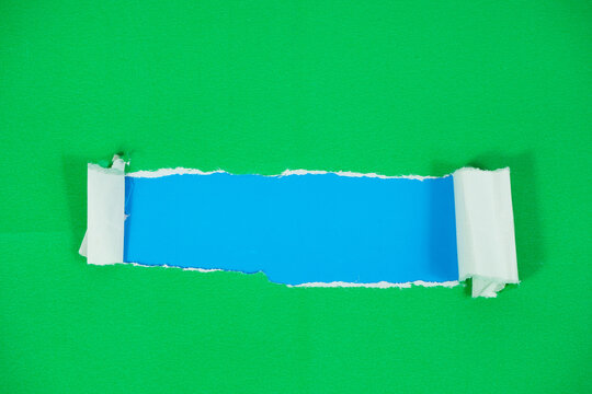 A blue paper layer revealed beneath a torn green paper layer. A torn paper section with space for text against a blue background. The torn green paper layer is pulled back, exposing the blue layer und