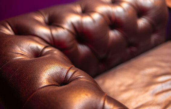 Close-up of luxury brown tufted leather sofa upholstery.