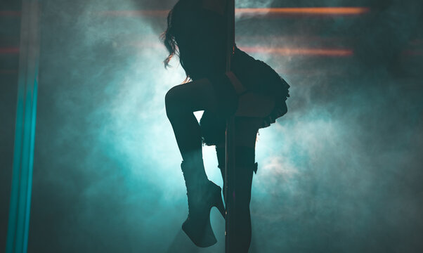 Sensual dancer performing in boots in a nightclub setting.