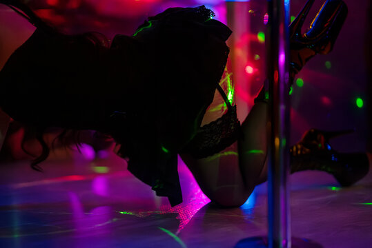 Female pole dancer lying on club stage.