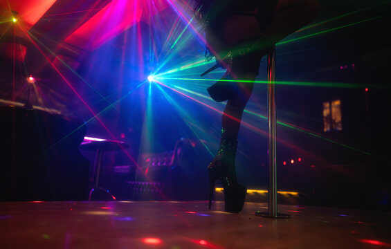 Pole dancer performing under laser lights in club.