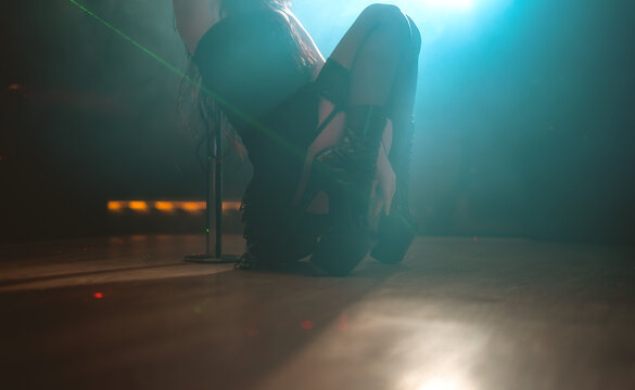 Sensual dancer performing in boots in a nightclub setting.