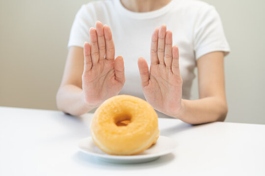 Diet concept, asian young woman hand push out, deny sugar donut, doughnut and sweet taste food on plate, fighting to keep it from getting fat when person bring to me. Healthy nutrition of weight loss.