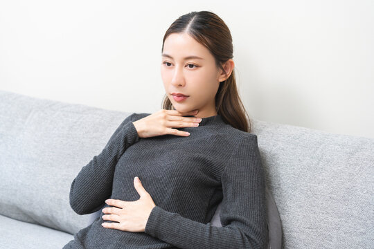 Acid reflux disease, suffer asian young woman have symptom gastroesophageal, esophageal, stomach ache and heartburn pain hand on chest from digestion problem after eat food, Healthcare medical concept