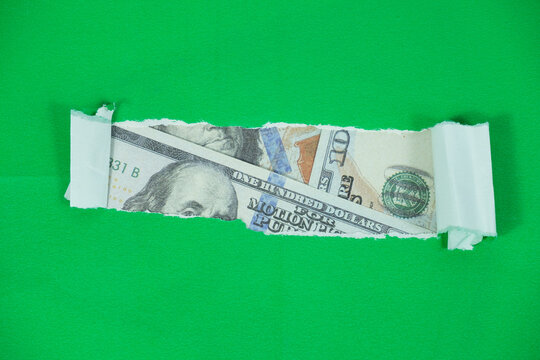 US dollars behind a torn green paper. Business and finance concept with copy space.

