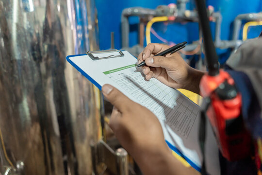 Electrical engineers are checking the maintenance systems of machinery in industrial plant. Professional engineering are taking note report data on equipment usage during work. Factory industry 