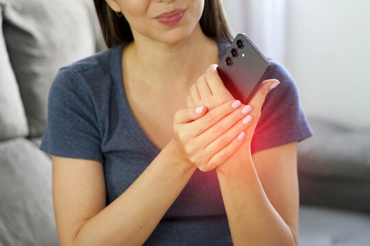 Close-up of a young woman holding her painful metacarpal due to prolonged smartphone use