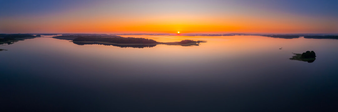 Panoramic aerial view of a golden sunrise over calm lakes