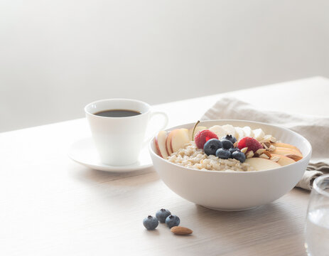 Healthy oatmeal breakfast bowl with fresh fruit and coffee