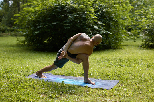 Practitioner balances in crow pose amidst lush greenery