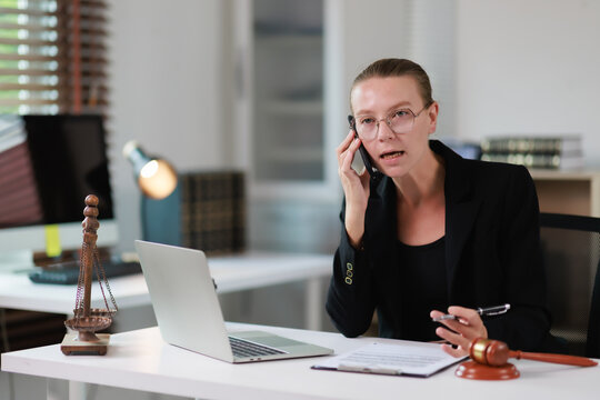 Female lawyer having an important phone conversation in her modern law office, actively managing client cases and providing legal advice with determination