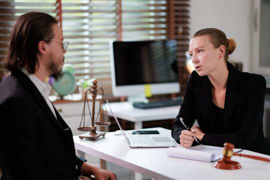 Female lawyer discussing legal matters with a male client in a professional office, advising on legal rights, justice, and court proceedings