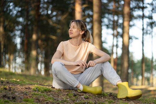 Calm woman sitting in pine forest, enjoying silence and sounds of nature, gazing into distance, peaceful moment, connection with nature, love for outdoors and inner harmony. Autumn season in woodland