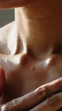 Vertical video: Right hand entering, woman pressing across bare collarbones at home, showing mole
