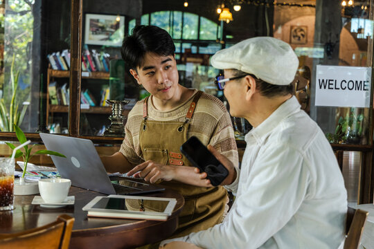 Modern cafe small business digital management concept with entrepreneur reviewing data on laptop, using technology for workflow planning, improving efficiency, decision making, business performance