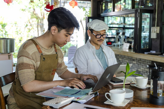 Modern small business digital technology, father and son cafe owner, young entrepreneur management, using laptop and tablet planning orders finance workflow efficiency technology business operation