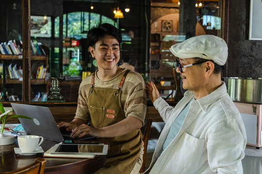 Modern small business digital technology, father and son cafe owner, young entrepreneur management, using laptop and tablet planning orders finance workflow efficiency technology business operation