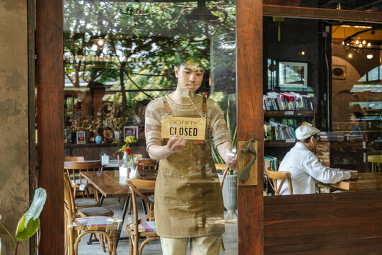 Small business cafe restaurant owner entrepreneur managing storefront with open or closed sign, young barista working daily routine with customer interaction, business operation in local coffee shop