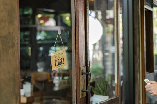 Small business cafe owner barista opening door while holding smartphone welcoming customer into coffee shop showing service interaction and daily business routine, young generation startup business