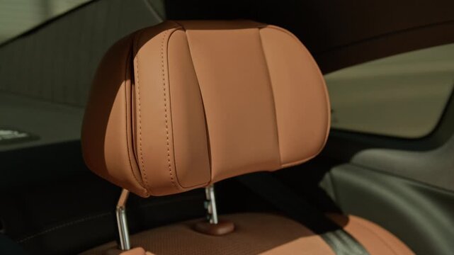 Luxury car seat with brown leather upholstery being showcased through slow tilt down camera movement. Ideal for automotive marketing, luxury car dealership promos, or leather manufacturing ads