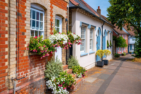 Charming historic houses with colourful doors and abundant flowers along a quiet street in Lavenham, Suffolk, one of England's best-preserved medieval villages.