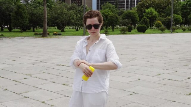 woman uses sunscreen before a city walk after cancer treatment, promoting responsible sun exposure and preventive self care in summer after a period of medical recovery