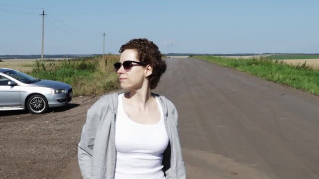 cancer survivor standing confidently beside a parked car on a rural road, showing independence, normal travel and an active life during long-term treatment