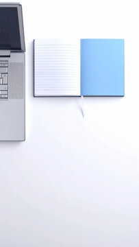 Laptop and open notebook on white desk with blue cover, lined paper, workspace, and copy space for planning
