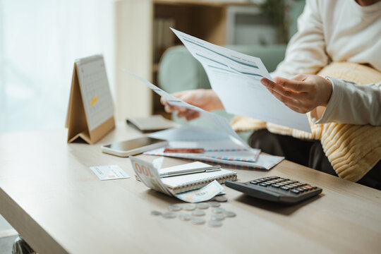 Budget review shows a woman sorting bills and cash beside a calculator, linking finance decisions, savings goals, and household expenses for commercial use. Expense tracking, receipt; expense focus.