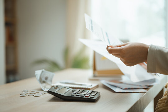 Budget paperwork is held above a calculator and coins, presenting finance review, savings awareness, payment planning, and recurring expenses. Household bills, debt; household focus.
