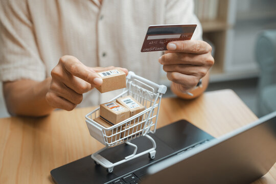 Shopping cart filled with packages is paired with a card and tablet, showing online purchase, digital payment, and active ecommerce delivery for commercial use. Parcel add, adding; parcel focus.