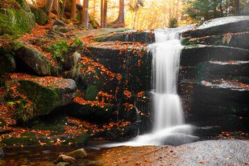 Naklejka premium Waterfall. Autumn landscape with waterfall in the mountain forest of the Karkonosze National Park in Poland, Europe