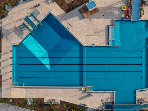 Aerial view of a modern swimming pool with clear blue water, lane markers, and surrounding tiled deck in Pattensen, Lower Saxony, Germany.