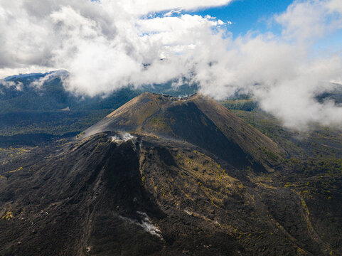 Aerial view of the Paricutin volcano featuring rugged volcanic slopes and surrounding mountainous terrain under a cloudy sky in San Juan Parangaricutiro, Michoacan, Mexico.