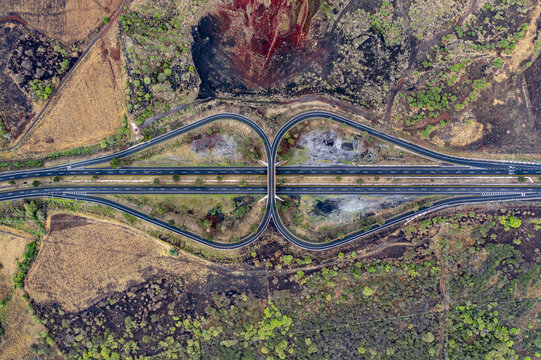 Aerial view of the Autopista Mexico - Puebla highway interchange surrounded by dry volcanic terrain and patches of vegetation in Ciudad de Mexico, Ciudad de Mexico, Mexico.