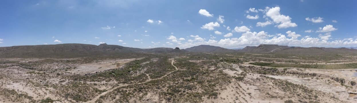 Aerial view of the arid desert landscape with scrubland, rugged hills, and a clear blue sky in Parras de la Fuente, Coahuila de Zaragoza, Mexico.