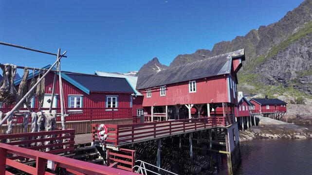 Picturesque red wooden fishing cabins, known as rorbuer, standing on stilts over the water in a traditional Norwegian fishing village