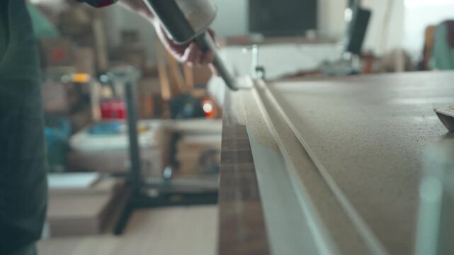 Hand running along a freshly cut walnut countertop edge to inspect the quality of the cut
