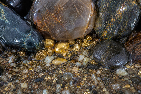 Wet river stones with golden nuggets particles close up water drops