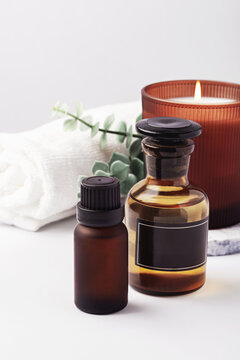 Aromatherapy spa background with a burning aroma candle, essential oil bottles, and green leaves, copy space