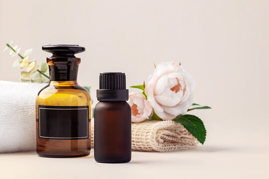 Spa and wellness background, essential oil bottles, towels with white roses and green leaves decoration, copy space