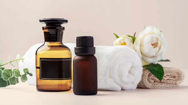 Spa composition, essential oil bottles, white towel with  roses and green leaf decoration