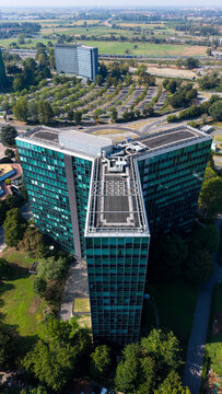 Aerial view of the Eni S.p.A. office building with its distinctive Y-shaped architecture surrounded by green spaces and parking areas in San Donato Milanese, Lombardia, Italy.