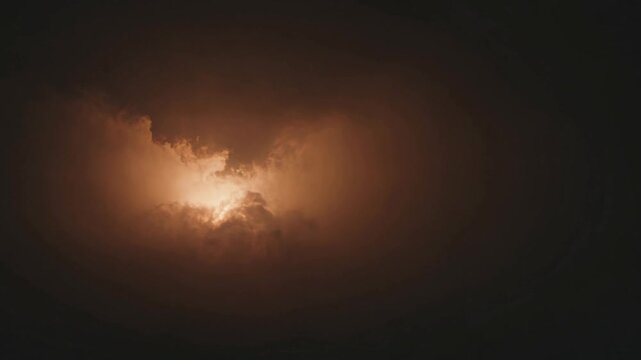 Dramatic sun shining through dark ominous storm clouds with a warm golden light, creating a breathtaking and moody skyscape with a sense of hope and mystery
