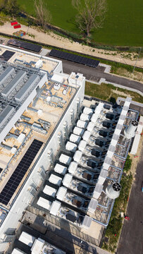 Aerial view of Vantage Data Centre - MXP1 featuring rows of industrial cooling units and solar panels on the roof in Melegnano, Lombardia, Italy.