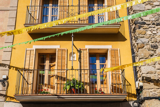 Sunlit yellow house facade with balconies and festive bunting