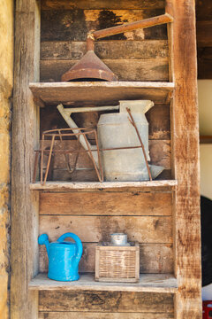 Vintage watering cans and rusty funnel on rustic wooden shelf